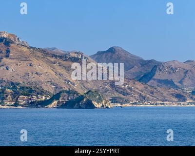 Taormina, Sizilien, Italien - 5. Juli 2024: Die Nordküste Taorminas mit den Felsen des Mazzaro im Zentrum. Stadtbild am Fuße der Bergkette Stockfoto