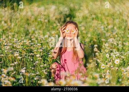 Porträt eines Mädchens in Kleid und Strohhut auf einem Kamillenfeld im Sommer Stockfoto