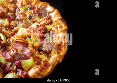 Blick von oben auf halbe Pizza mit Käse Schinken Speck und Peperoni auf isoliertem schwarzen Hintergrund mit heißem dampfendem Rauch. Essen und Kochen Stockfoto