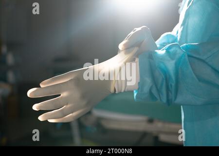 Mittelschnitt einer birassischen Chirurg mit Operationskleid und Handschuhen im Operationssaal Stockfoto