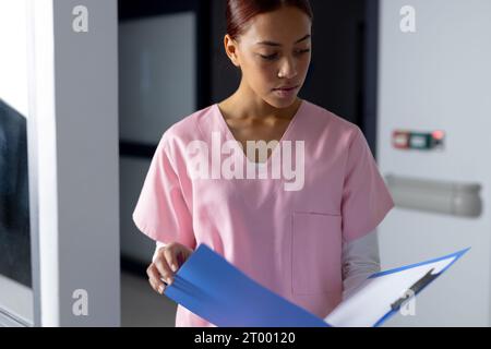 Birassische Ärztin trägt Kittel, die Dokumente im Flur des Krankenhauses halten Stockfoto