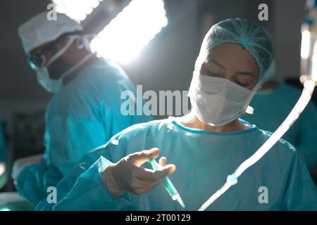 Birassische Chirurg in Operationskittel mit Tropfinfusion im Operationssaal des Krankenhauses Stockfoto