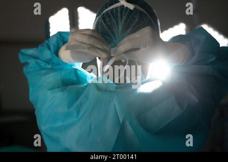 Birassische Chirurgin mit Operationskittel und Gesichtsmaske im Operationssaal des Krankenhauses Stockfoto