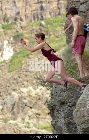 Die junge Frau springt vom Felsen. Stockfoto