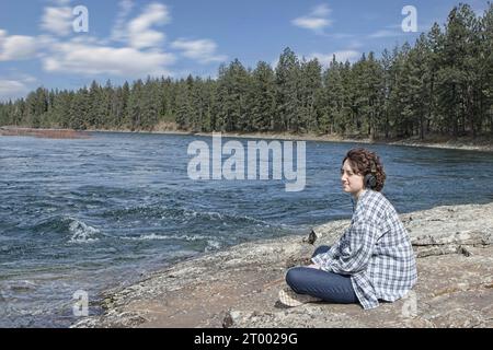 Die junge Frau genießt einen sonnigen Tag am Fluss. Stockfoto