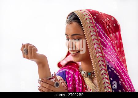 Nahporträt einer jungen Frau Rajasthani, die Armreifen vor weißem Hintergrund betrachtet Stockfoto