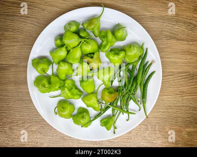 Grüne Chilischoten auf weißem Teller Stockfoto