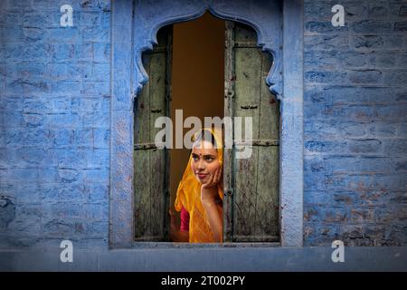 Rajasthani, junge Frau, die mit Hand auf Wange durch das Fenster schaut Stockfoto