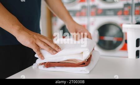 Hausmann mit Korb und schmutziger laundryÂ gewaschener Kleidung im Waschraum. Waschen machineÂ im Wäschereigeschäft Stockfoto
