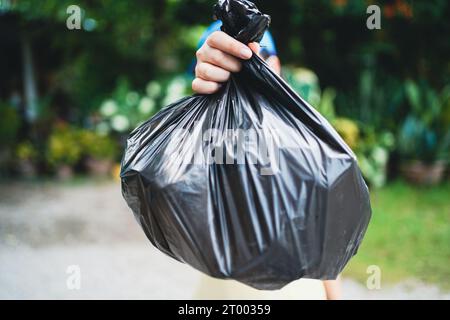 Freiwillige Wohltätigkeitsorganisation womanÂ Hand hält Müllbeutel und Plastikflaschenmüll zum Recycling für die Reinigung im Park Freiwilligendienst Stockfoto