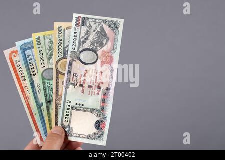 Nepalesisches Geld in der Hand auf grauem Hintergrund Stockfoto