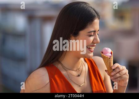 Close-up-Porträt einer jungen Frau, die Eis im Kegel isst Stockfoto