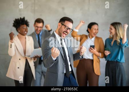 Das Team ist begeistert von verschiedenen Geschäftsleuten und feiert gemeinsam im Büro den Unternehmenssieg Stockfoto