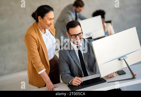 Geschäftsleute mit Kollegen im Büro überwachen Bestandsdaten auf dem Bildschirm und analysieren den Preisfluss Stockfoto