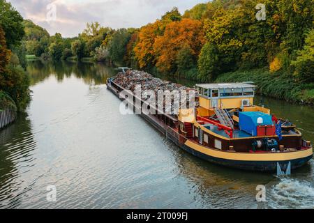 Transportindustrie. Schiffskahn transportiert Schrott und Sand mit Kies. Der mit Metallschrott beladene Lastkahn ist auf der Straße Stockfoto