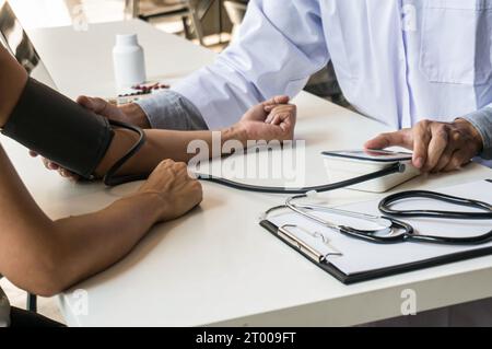 Arzt im Gesundheitswesen. Berufsarzt im weißen Uniform-Mantel Interview mit dem Patienten, der seine männliche Patie beruhigt Stockfoto