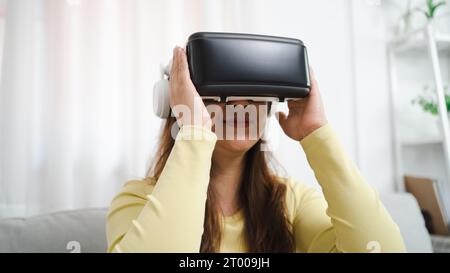 Junge asiatische Frau, die während des VR Experience Future Technology Konzepts virtuelle Realität in Berührung bringt. Stockfoto