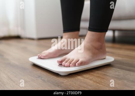 Fettdiät und Schuppenfüße stehen auf elektronischen Waagen zur Gewichtskontrolle. Messgerät in Kilogramm für eine Diätkontrolle. Stockfoto