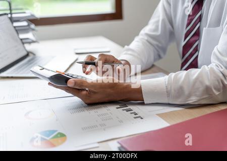 Geschäftsmann Buchhalter Analyse von Investitionsdiagrammen Rechnung und Drücken von Rechnerschaltflächen über Dokumenten. Buchhalter Stockfoto