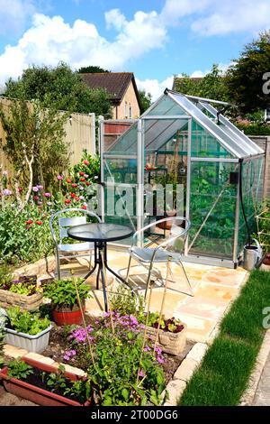 Neues modernes Polycarbonat-Hybridgewächshaus mit Tisch und Stühlen im Vordergrund, Somerset, Großbritannien, Europa Stockfoto