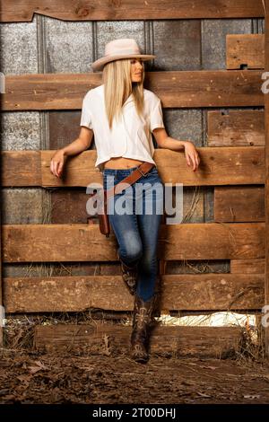 Ein hübsches blondes Model in Western Gear steht draußen und genießt das Frühlingswetter Stockfoto