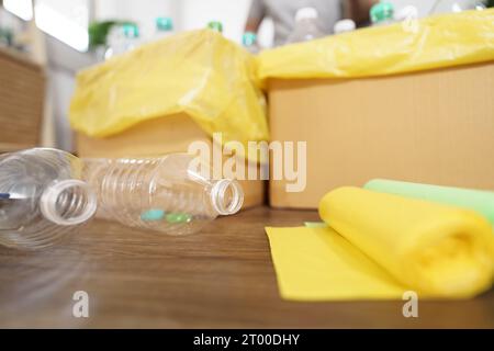 Recyceln Sie den umweltfreundlichen Zero Concept-Mann, der leere Plastikflasche in den Recyclingbehälter mit gelben Mülltüten zu Hause wirft Stockfoto