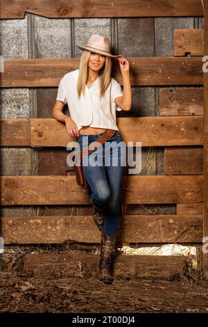 Ein hübsches blondes Model in Western Gear steht draußen und genießt das Frühlingswetter Stockfoto