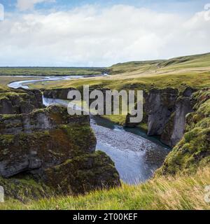 Der Fluss Fjadra fließt durch den wunderschönen Canyon Fjadrargljufur. Südisland. Bewölkter Herbsttag. Es befindet sich in der Nähe des Ringes Stockfoto