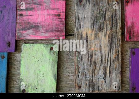 Stücke von verwittertem lackiertem Holz, auf Holzdielen genagelt. Stockfoto