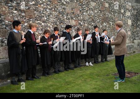 Öffentliche Schulbildung, Internat der 2020er Jahre Großbritannien. Winchester College jährliche Illumina-Zeremonie. „College Junior Men“ Dies sind Jungen, die Gelehrte sind, die Kerzen in Nischen in der mittelalterlichen Meads Mauer anzünden. (Die Wand, die ein Spielfeld umgibt.) Mit einem Schulmeister vor der Mauer sagen und singen sie einen kurzen Strophe auf Latein. Winchester, Hampshire, England, 9. Dezember 2022. HOMER SYKES AUS DEN 2020ER JAHREN. Stockfoto