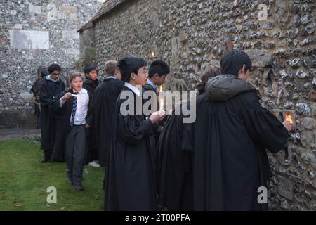 Privatschule Großbritannien. Winchester College jährliche Illumina-Zeremonie. „College Junior Men“ Dies sind Schüler, die Gelehrte sind, Lichtkerzen in Nischen in der mittelalterlichen Meads-Mauer. (Die Wand, die ein Spielfeld umgibt.) Winchester, Hampshire, England, 9. Dezember 2022. HOMER SYKES AUS DEN 2020ER JAHREN. Stockfoto