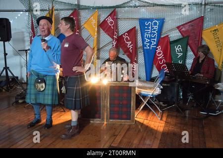 Schottische Ceilidh singt traditionelle Volkslieder der Fischer. Cockenzie and Port Seton Friendly Society of Fishermen, The Box Meeting Ceilidh. Der ehemalige Fischer und Skipper Archie Johnston (86 Jahre) und Gareth Jones sangen Aberlady Bay: „Der Blaue liegt vor uns, Jungs, der Wind weht fair und frei, das Boot gleitet über die Kammwelle, als würde sie hame ... sein September 2023 Cockenzie und Port Seton, East Lothian, Schottland. HOMER SYKES AUS DEN 2020ER JAHREN Stockfoto