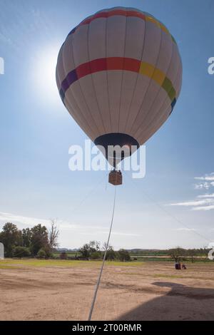 Aufsteigender Heißluftballon. Luftfahrzeug an drei festen Punkten befestigt Stockfoto