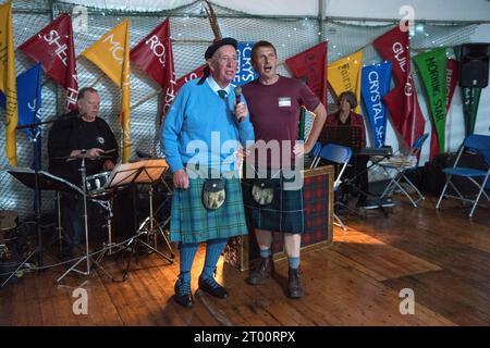 Schottland Kilt. Schottische Ceilidh singt traditionelle Volkslieder der Fischer. Cockenzie and Port Seton Friendly Society of Fishermen, The Box Meeting Ceilidh. Der ehemalige Fischer und Skipper Archie Johnston (86 Jahre) und Gareth Jones sangen Aberlady Bay: „Der Blaue liegt vor uns, Jungs, der Wind weht fair und frei, das Boot gleitet über die Kammwelle, als würde sie hame ... sein September 2023 Cockenzie und Port Seton, East Lothian, Schottland. HOMER SYKES AUS DEN 2020ER JAHREN Stockfoto