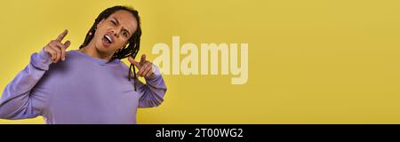 Verwirrter und schockierter afroamerikaner in lila Sweatshirt mit piercenden Fingern, Banner Stockfoto