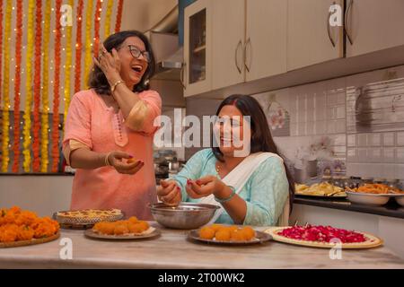 Schwestern in Laws unterrichten einander, wie man Ladoos (traditionelle indische Süßigkeit) während des Diwali-Festivals macht Stockfoto