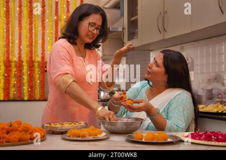 Schwiegermutter Lehre Tochter im Gesetz, wie man macht Ladoo aus Anlass von Diwali Stockfoto