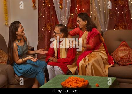 Großeltern und Enkelin sprechen im Wohnzimmer auf Diwali Stockfoto