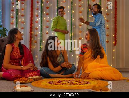 Freunde haben Spaß beim Dekorieren des Bodens mit Blumen ( Rangoli) anlässlich von Diwali Stockfoto