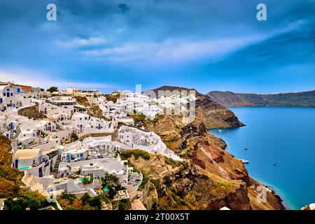 Luftaufnahme der berühmten Caldera-Bucht auf Santorin, Ägäis, Griechenland, weiß getünchte Häuser von Thira oder Fira Stadt, Insel Nea Kameni am bedeckten Tag. Schwere Wolken, dramatischer Himmel, Kreuzfahrtschiffe betreten den Hafen eines berühmten Touristenziels. Stockfoto