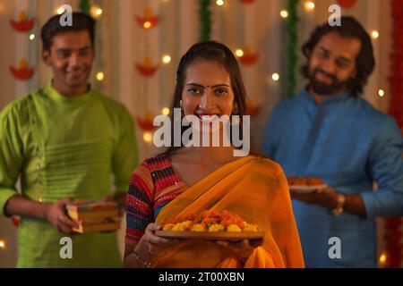 Lächelnde Frau mit Ringelblumen und ihre Freunde stehen hinter der Diwali-Feier Stockfoto