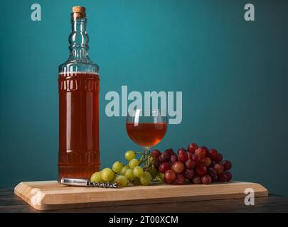 Rotwein in einer Flasche und Glas mit roten und grünen Trauben Stockfoto