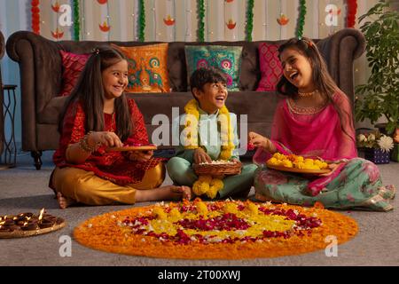 Kinder haben Spaß beim Dekorieren des Bodens mit Blumen ( Rangoli) anlässlich von Diwali Stockfoto