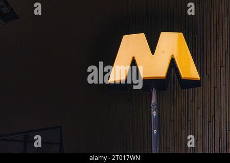 Der berühmte und unverkennbare Markenzeichen „m“ für Metro oder U-Bahn direkt am Hauptbahnhof, der Pendler in Richtung U-Bahn-Eingang führt. Rotterdam, Niederlande. Bild auf analogem, altem Kodak Film. Stockfoto