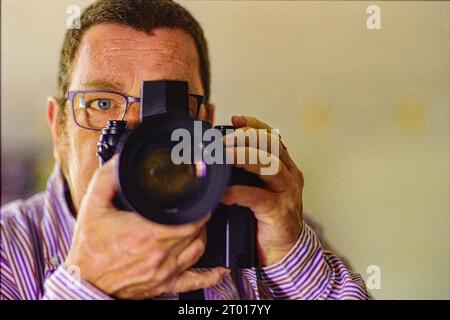 Selbstporträt mit der analogen Nikon F3 Fotokamera im Innenspiegel. Tilburg, Niederlande. Stockfoto