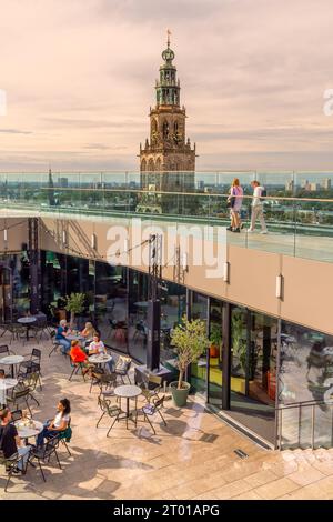 Groningen, Niederlande - 26. September 2023: Dach der Bibliothek Forum Groningen mit Touristen vor dem berühmten Kirchturm Martinitoren Stockfoto