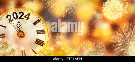 2024 Neujahr mit Uhr bis Mitternacht mit defokussiertem goldenem Hintergrund und Feuerwerk Stockfoto