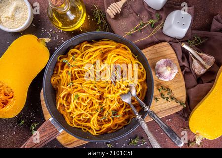 Hausgemachte Herbstkürbis-Spaghetti-Pasta, vegane mediterrane, amerikanische vegane Aufwärmgerichte mit käsiger Kürbissauce, Knoblauch und Thymian, dunkler Beton b Stockfoto