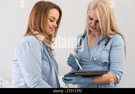 Schritte zur Genesung: Der Arzt zeigt der Frau auf der Tablette die Testergebnisse und spricht über die Möglichkeiten der Verbesserung der Gesundheit. Patientenversorgung: A Stockfoto