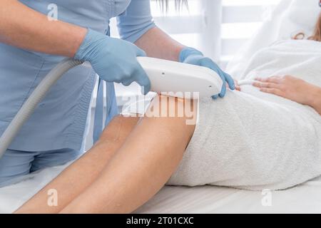 Entdecken Sie das Geheimnis der makellosen glatten Haut, wo auf dem Foto die Kosmetikerin das Verfahren Laser-Photoepilierung in einer Schönheitsklinik demonstriert Stockfoto